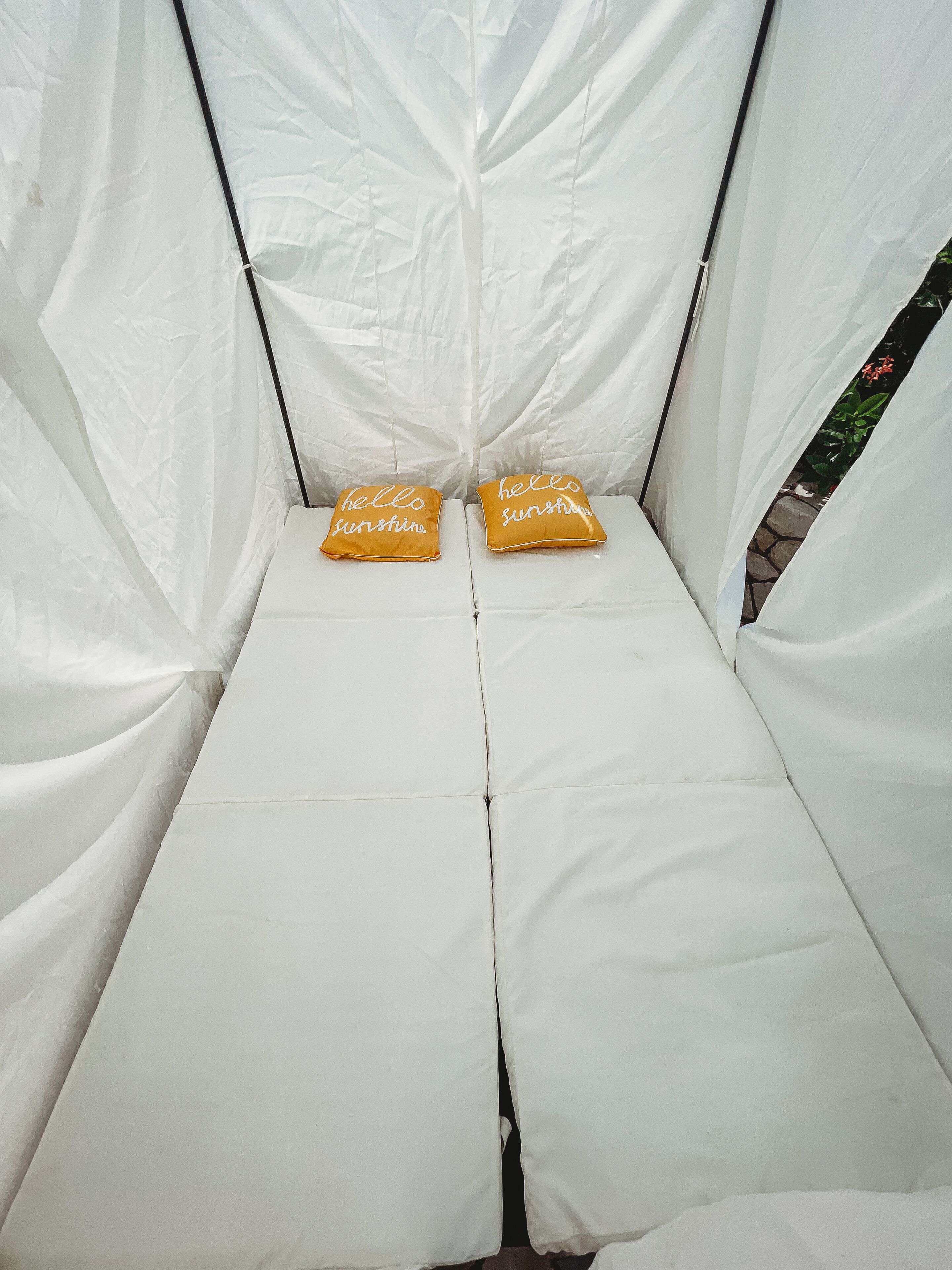 A white tent-like structure with two yellow pillows on a white mattress.