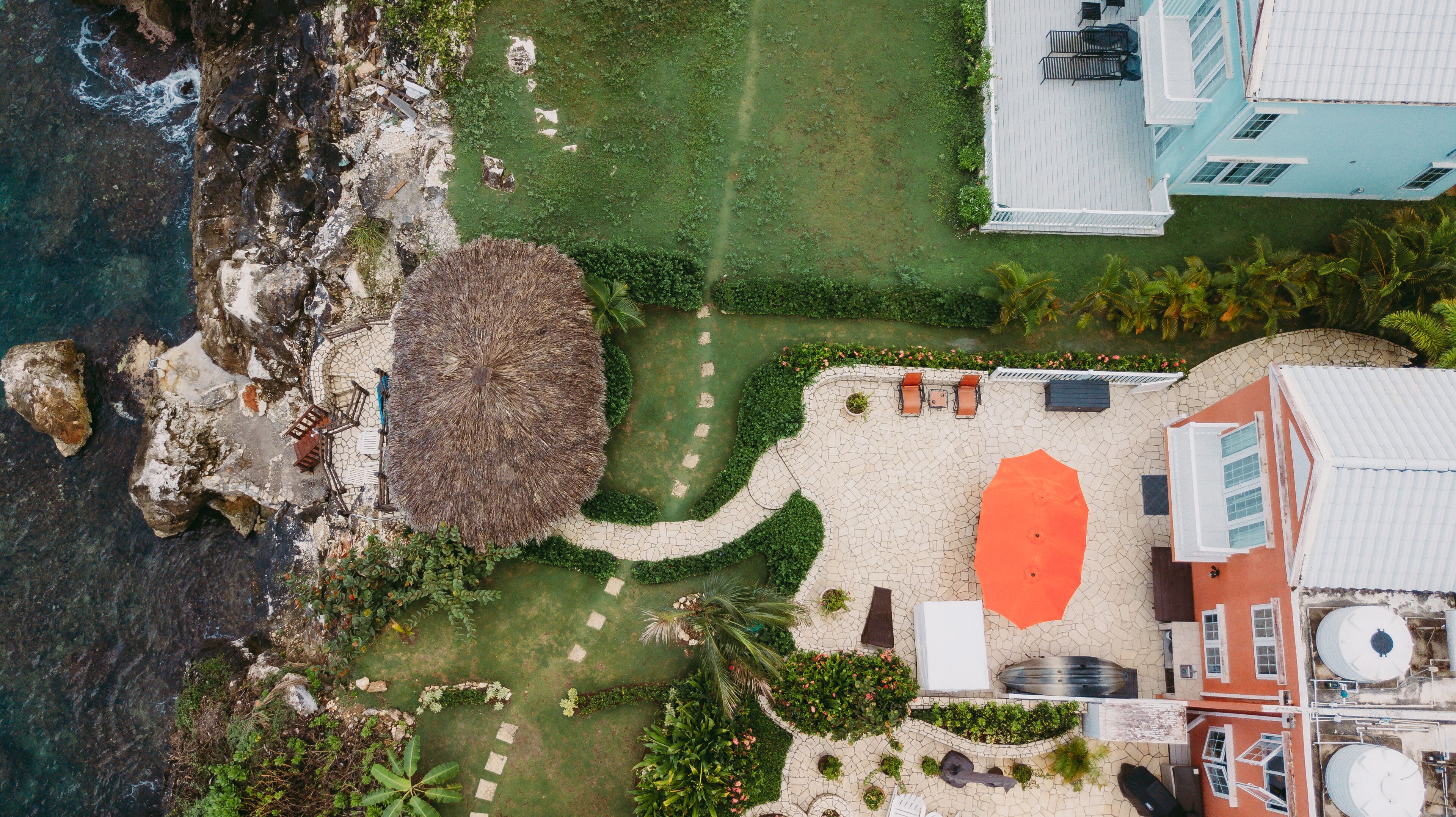Vista aérea de un resort con piscina, zona de descanso y una gran estructura de techo de paja.