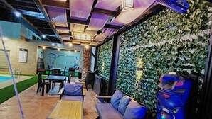 Un espacio interior con asientos, una piscina y una pared cubierta de vegetación.