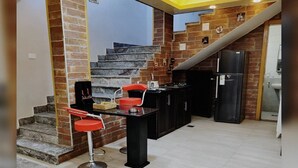 Una cocina moderna con una isla central, taburetes rojos y una escalera que lleva a un nivel superior.