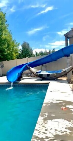 A swimming pool with a blue slide. - Walkout Basement Apt w/ Waterslide, Hot Tub & More
 (South Jordan)