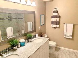 A bathroom with two sinks, a large mirror, and a towel rack with multiple towels. - Walkout Basement Apt w/ Waterslide, Hot Tub & More
 (South Jordan)