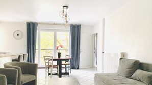 Een moderne woonkamer met een bank, stoelen, een eettafel en een hanglamp.
