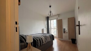 Een moderne slaapkamer met een bed, bedlampje, kledingkast en uitzicht op buiten.