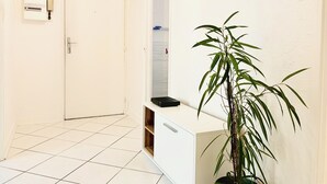 Een schone, witte gang met een deur, een telefoon en een plant in pot.