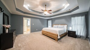 Un dormitorio con cama, mesita de noche, cómoda y ventilador de techo.