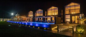A modern hotel with a pool area, outdoor seating, and large windows.