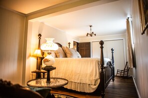 A bedroom with a bed, a nightstand, a lamp, and a chair.
