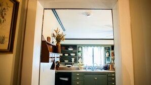A kitchen with green cabinets, a sink, and various kitchen items.
