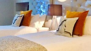 Une chambre d’hôtel avec un grand lit, une tête de lit capitonnée et plusieurs oreillers.