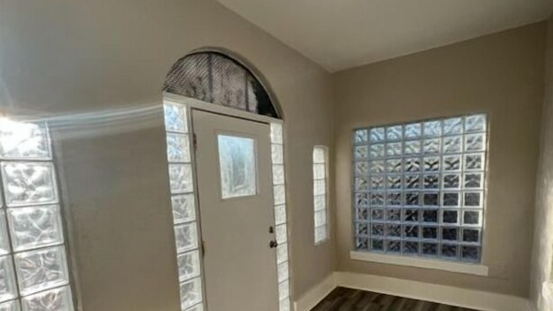 A hallway with a wooden floor, a door with a window, and a window with a grid pattern. - Historic University 3BR  (Tucson)