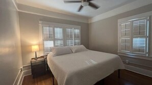 A bedroom with a bed, a nightstand, a lamp, a ceiling fan, and windows with blinds. - Historic University 3BR  (Tucson)