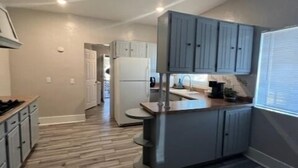 A modern kitchen with grey cabinets, a central island, and a view into the dining area. - Historic University 3BR  (Tucson)