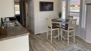 A compact kitchen with a dining area, a balcony, and a welcome sign.