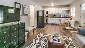 Une cuisine moderne avec des meubles blancs, un four encastré et un coin repas comprenant une table et des chaises.