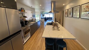 A modern kitchen with a central island, stainless steel appliances, and a dining area with a view. - Peaceful View Home with a Cozy Modern feel walking distance to the beach (Seattle)