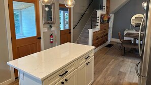 Una cocina con encimera de mármol, armarios de madera e iluminación colgante.