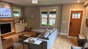Una sala de estar moderna con un sofá gris, una mesa de centro, un televisor y una chimenea.