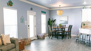 Ein geräumiges Wohnzimmer mit grauem Sofa, einem Couchtisch und einem Essbereich mit Holztisch und Stühlen.