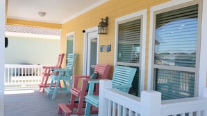 Eine Veranda mit bunten Adirondack-Stühlen und einem weißen Geländer.