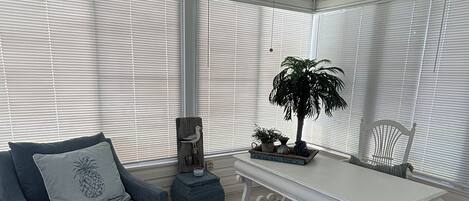 A room with a grey sofa, a white table, and a ceiling fan.