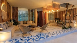 A modern living room with a sofa, two armchairs, a coffee table, and a patterned floor.