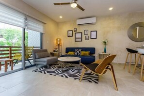 Un salon moderne avec un canapé, des fauteuils, une table basse et un balcon offrant une vue agréable.