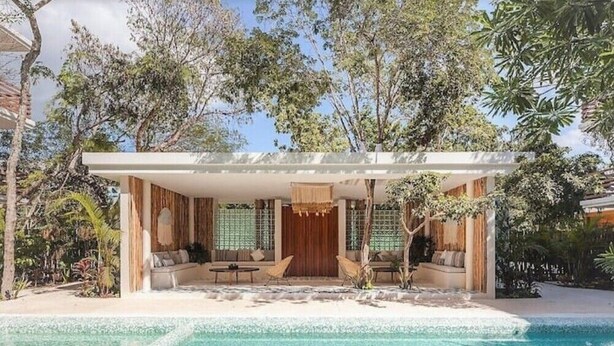 A modern villa with a pool, outdoor seating, and lush greenery.
