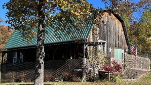 A rustic barn-style building with a green metal roof, a wooden fence, and a sign that reads "Pioneer Family."