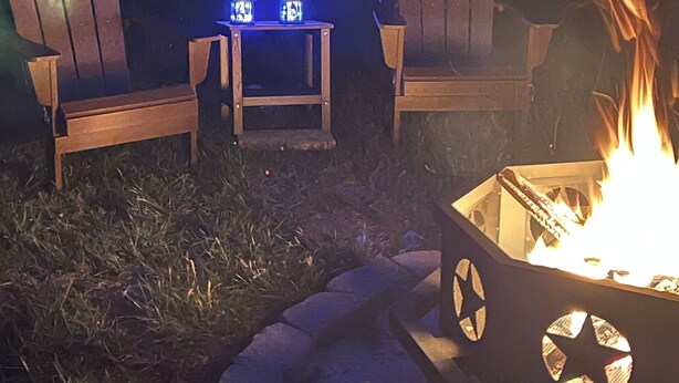 A fire pit with chairs and lanterns in a nighttime outdoor setting.