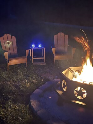 A fire pit with chairs and lanterns in a nighttime outdoor setting.