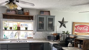A kitchen with grey cabinets, a microwave, a stove, and a ceiling fan.