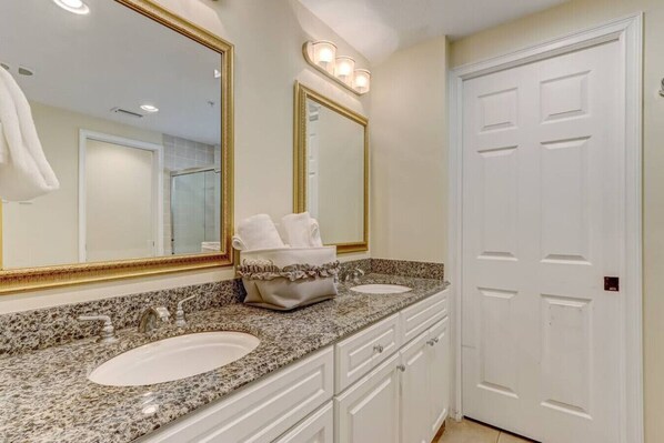 A bathroom with two sinks, a vanity with drawers, a large mirror with lights, and a white door. - Spacious,Ultimate Comfort,Privacy,AIP Resort . (Fernandina Beach)