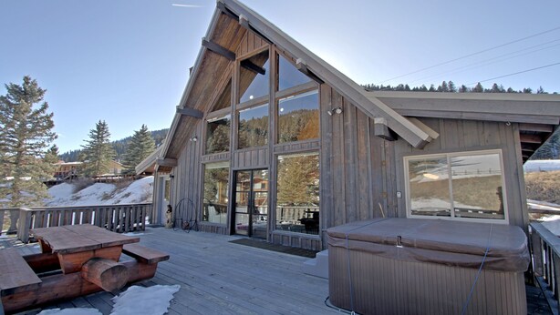 A wooden cabin with large windows, a deck, and a hot tub. - "Peace Like a River" mountain cabin on river - Red River, NM. Hot tub optional. (Red River)