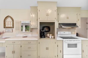 A kitchen with cream-colored cabinetry, a built-in stove, and a coffee maker. - K K’s Hideaway—pond/pool table 

 (Hattiesburg)