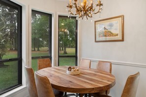 A dining area with a round wooden table, six chairs, and a chandelier. - K K’s Hideaway—pond/pool table 

 (Hattiesburg)