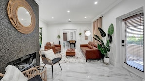 Una sala de estar moderna con chimenea, dos sofás, una mesa de centro y un espejo grande.