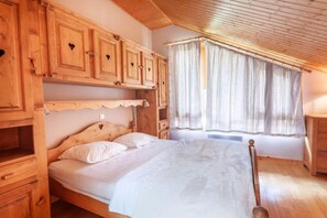A wooden bedroom with a bed, built-in cabinets, and a window with curtains. - 200m from resort center, 2nd floor, balcony, tv, 130m², Morzine (Morzine)