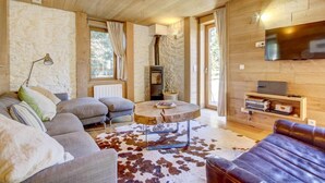 A cozy living room with a stone wall, a fireplace, a television, and a cowhide rug. - 1st floor, terrace, balcony, fireplace or stove, tv, ski locker, 82m², Morzine (Morzine)