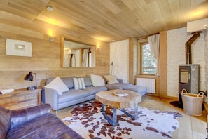 A cozy living room with a sofa, a coffee table, a fireplace, and a stone wall.