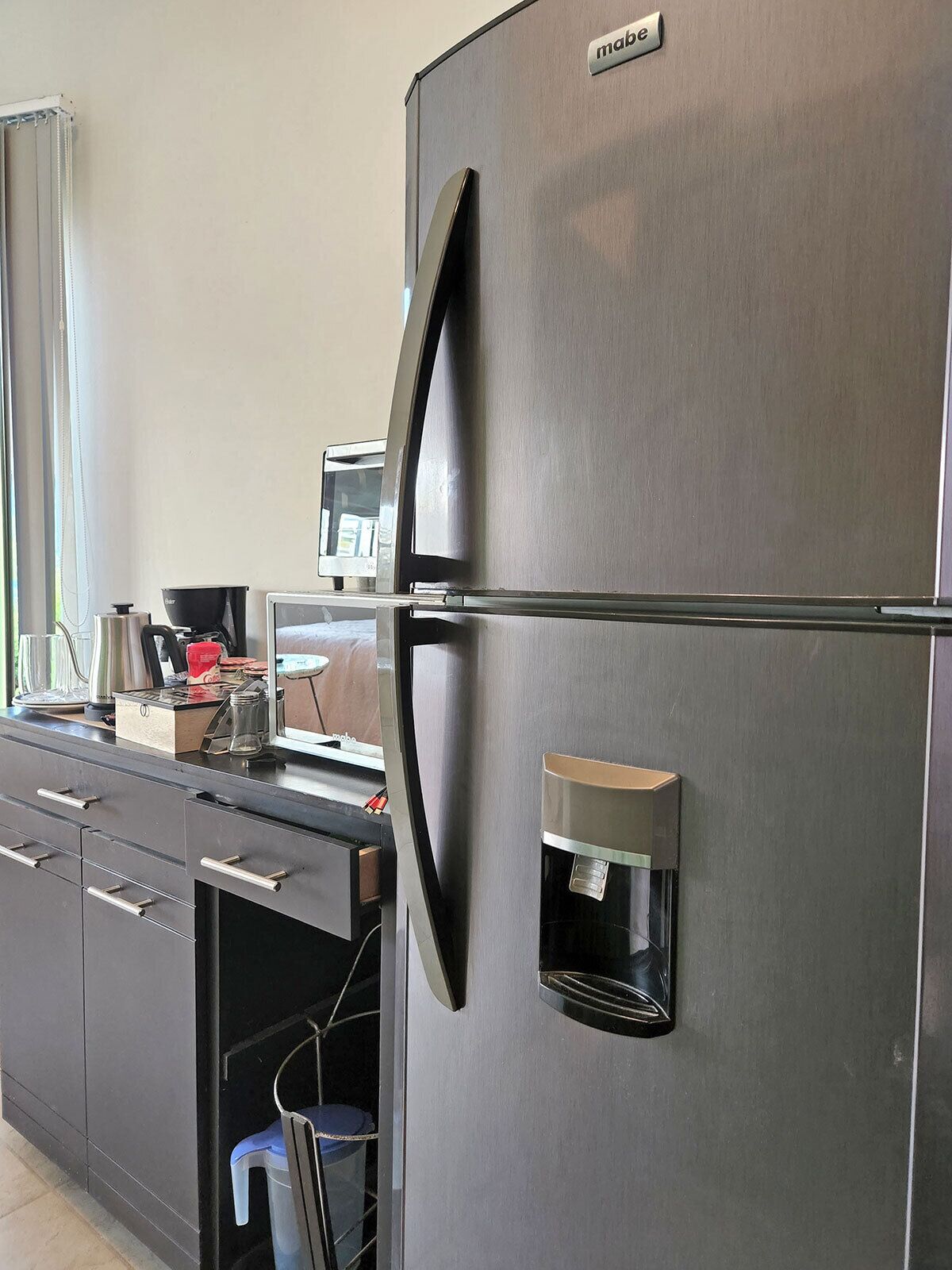 Une cuisine moderne équipée d’un réfrigérateur en acier inoxydable, d’une machine à café intégrée et d’un petit évier.