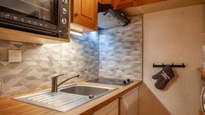 A compact kitchen with a modern design, featuring a stainless steel sink, a microwave, and wooden cabinets. - 1st floor, balcony, tv, ski locker, 25m², Morzine (Morzine)