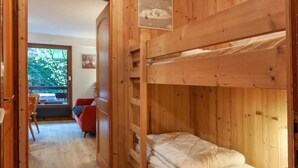 A wooden cabin with bunk beds, a red chair, and a window with a view of trees. - 1st floor, balcony, tv, ski locker, 25m², Morzine (Morzine)