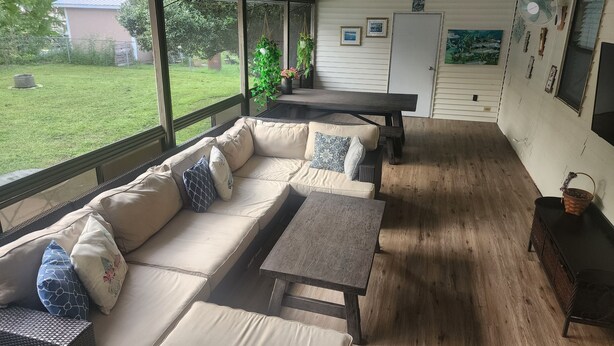 A covered patio with a sofa, table, and chairs.