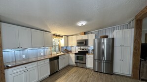Una cocina moderna con armarios blancos, electrodomésticos de acero inoxidable y encimera de madera.