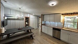 Una cocina moderna con suelo de madera, armarios blancos y un horno empotrado.