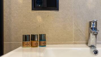 A bathroom sink with three bottles of HORMONE body lotion.