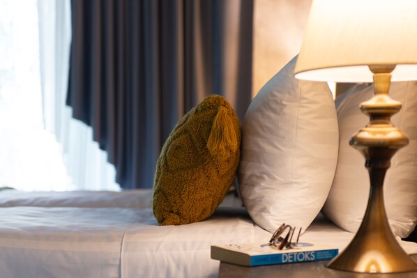 Una cama bien hecha con un almohadón verde, un almohadón blanco y un libro titulado 