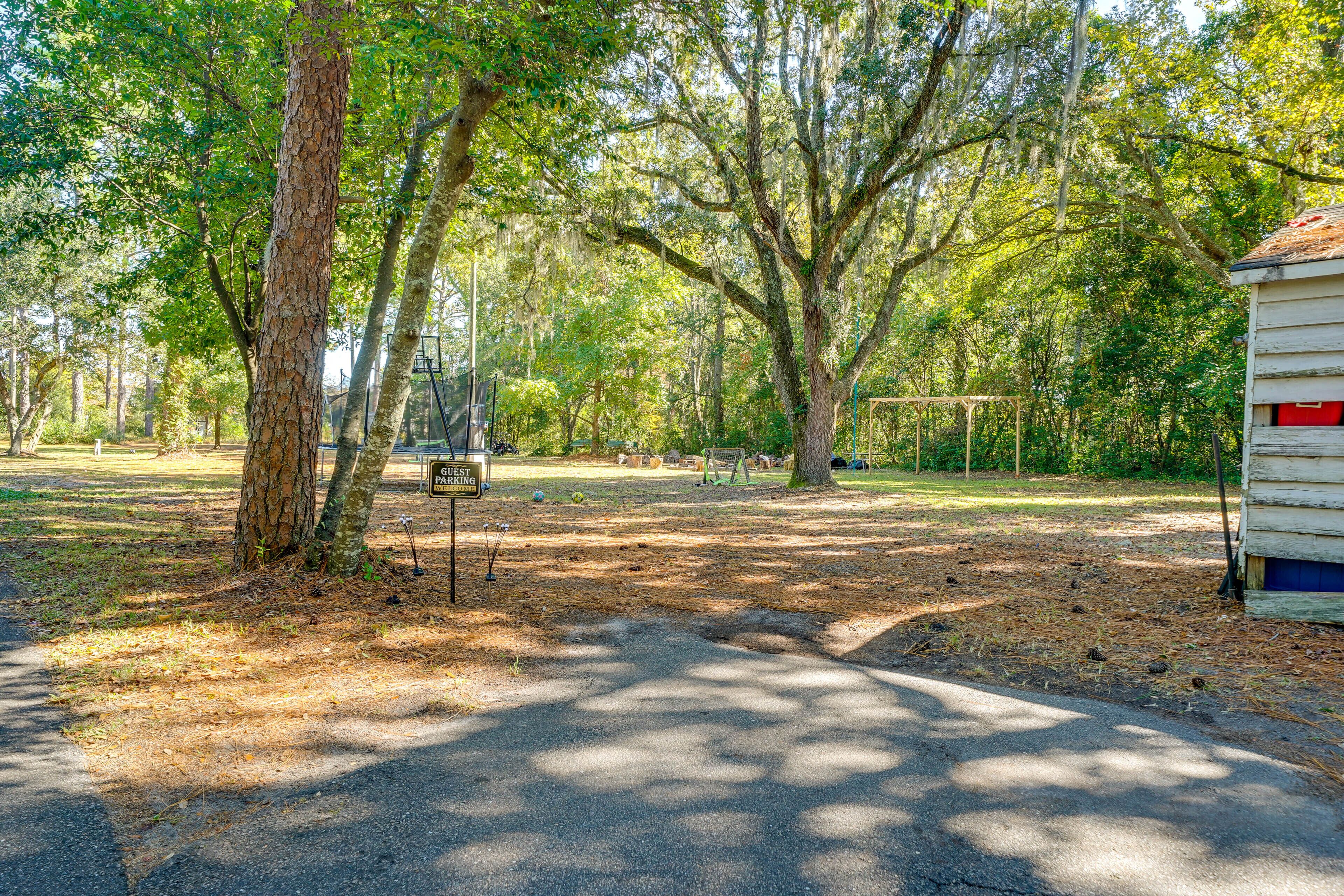 A campground with a "6-guest parking" sign, surrounded by trees and a wooden cabin.