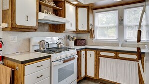 Una cocina con armarios de madera, estufa y ventana con persianas.